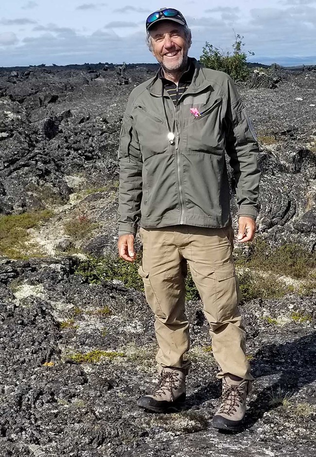 A man stands on a lava field.