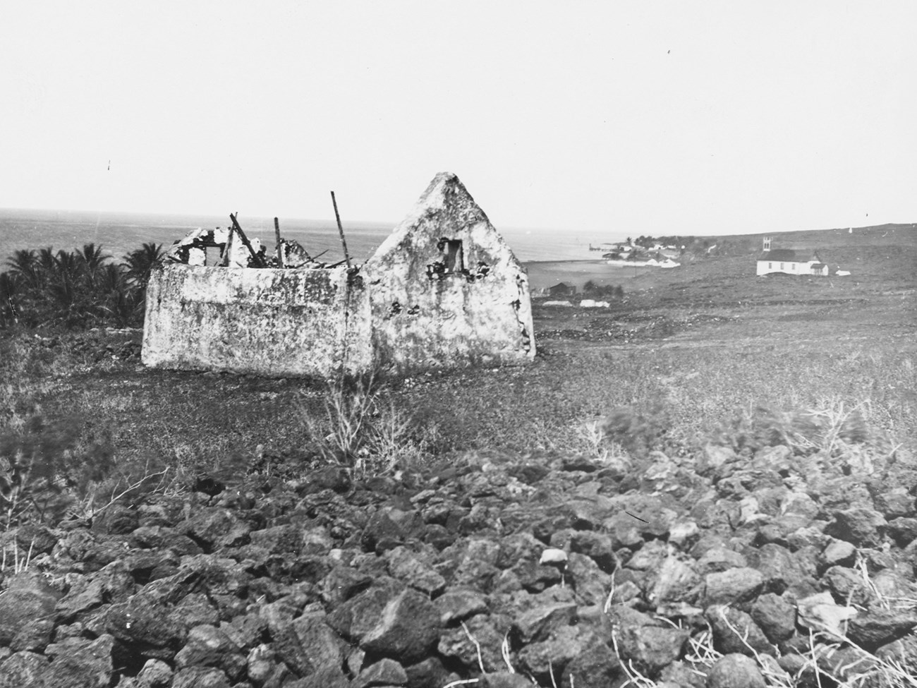 Black and white photograph of deteriorating hut surrounded by rocks