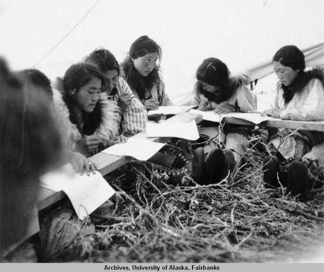 Black-and-white photograph of young Nunamiut women in school inside a wall tent