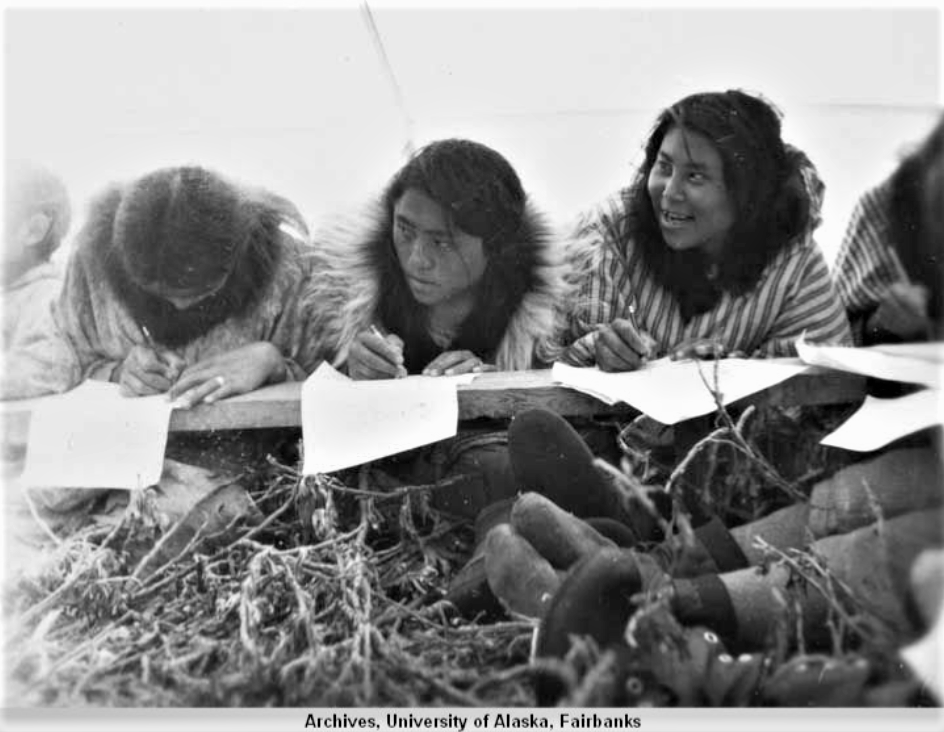 Black-and-white photograph of young Nunamiut women at school in a wall tent