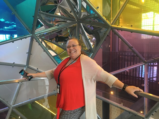 A woman standing inside a colorful, geometric sphere