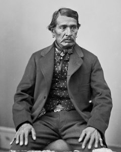 A historic photo of a man sitting, wearing a suit.