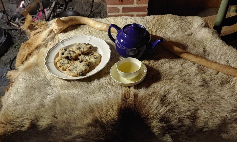 small round cookies, and a tea pot sit on an elk hide.