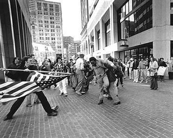 Photo of a teenage attacking a black man in a suit with the American Flag outside of Boston's City Hall