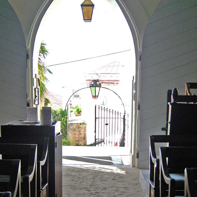 Interior of St. Thomas today View down aisle, wooden pews on either side, looking out the arched doorway into the front courtyard.