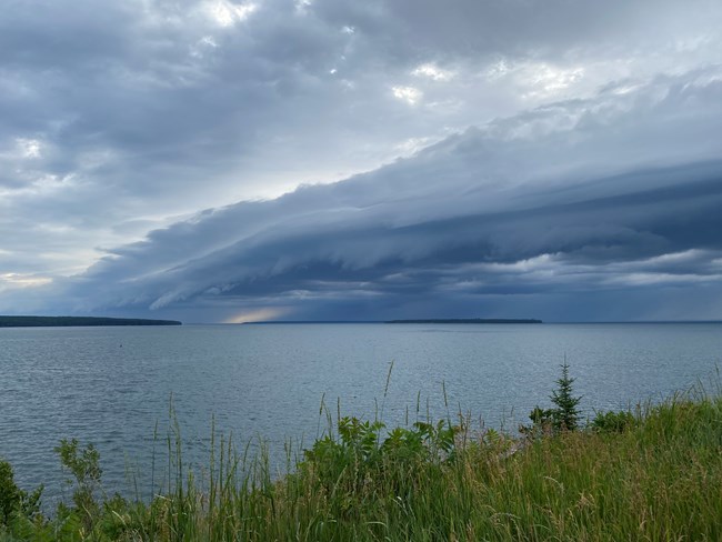 Dark storm clouds form over an island in the distance and lake.