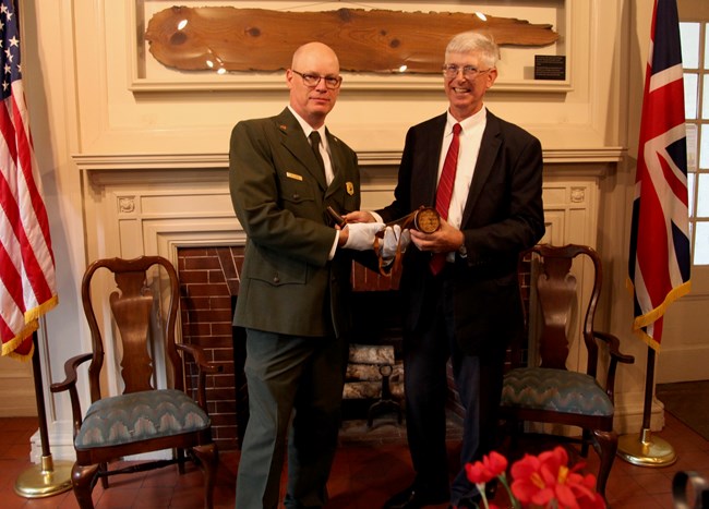 A National Park Service Ranger and a man in a suit holding a powder horn