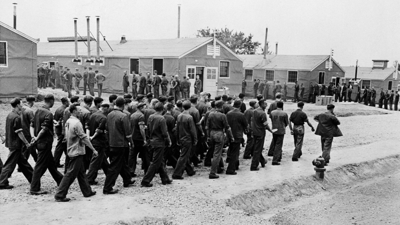 A line of men walking at a WW2 prisinor of war camp