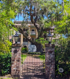 Large tan colored mansion surrounded by live oaks and spanish moss
