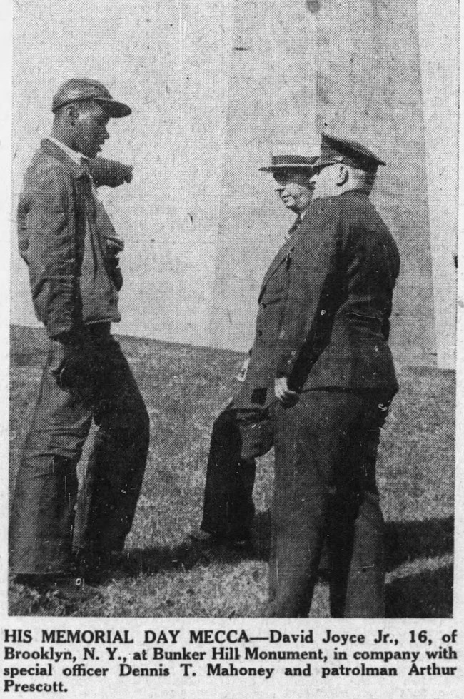 Newspaper clipping of a young African American standing in front of the Bunker Hill Monument with two police officers.
