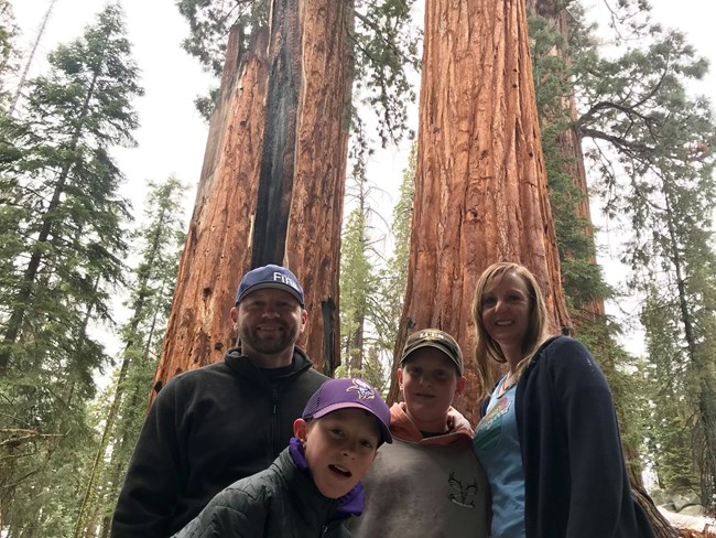 Todd and his family in Sequoia National Park A man, wife, and two boys stand smiling in front of giant Sequoia trees.