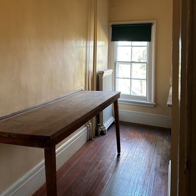 A narrow room with long table attached to the wall.