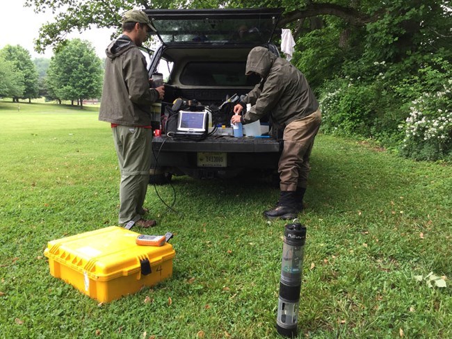 Two scientists getting their gear ready to take water quality samples in the field.