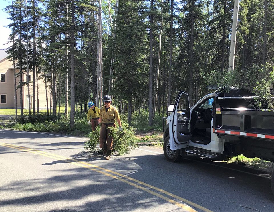 WRST HQ 2020 BuckingLog 3 people - NPS Photo_Edit Two wildland firefighters haul limbs to a trailer.