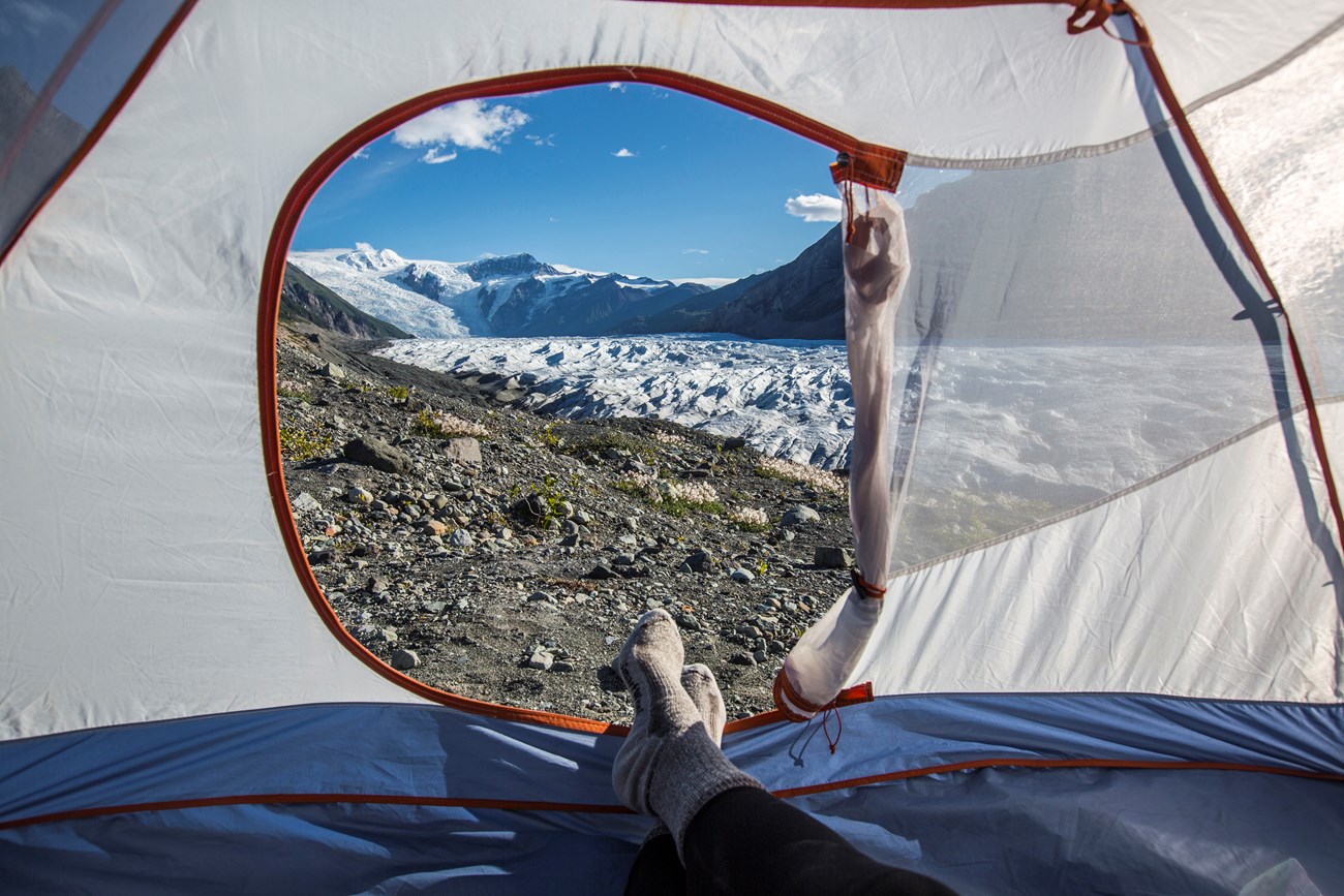 A hiker enjoys the mountainous view from their tent.