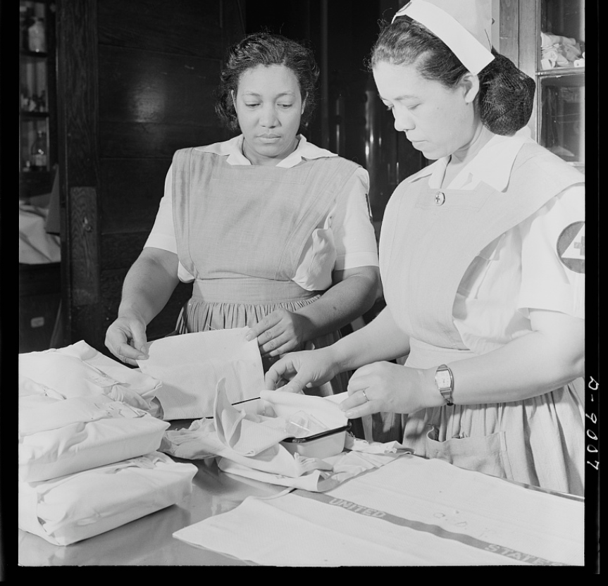 Black and white photo of two African American nurses putting together a box of supplies.