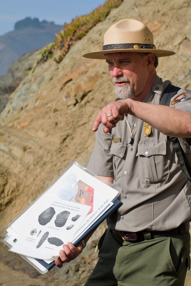 Park ranger gestures to fossil diagram.