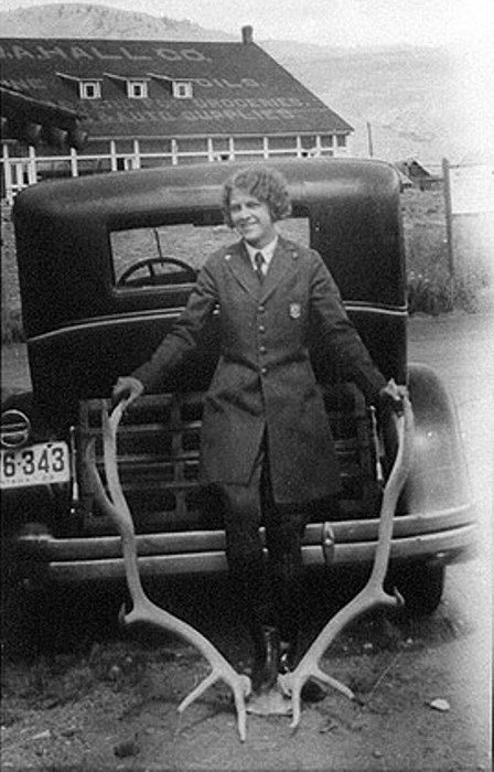 YELL 42774-04 Ranger Frances Eva Pound in her Park Service uniform stands in front of a car, holding onto large antlers.