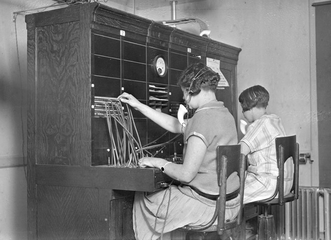 Two women sit at a switchboard working Yosemite's telephone exchange.