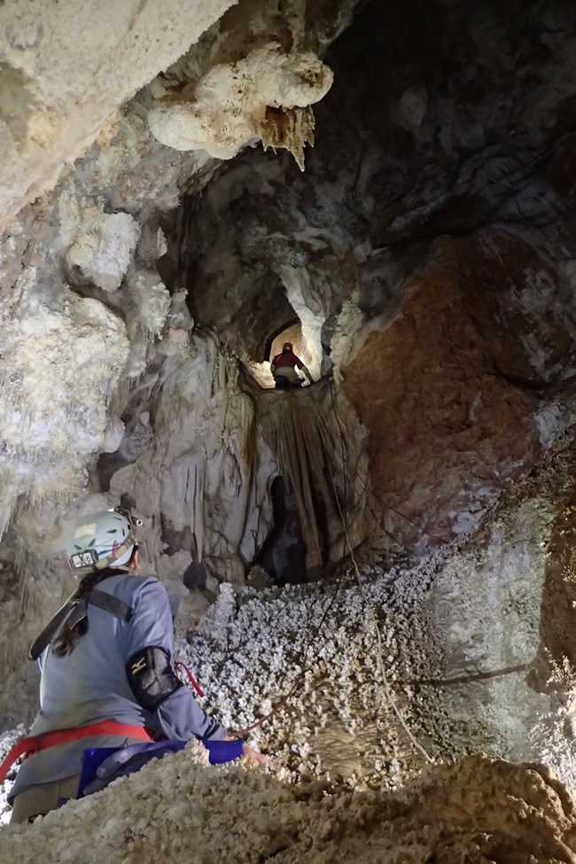 a person belaying a climber in a cave