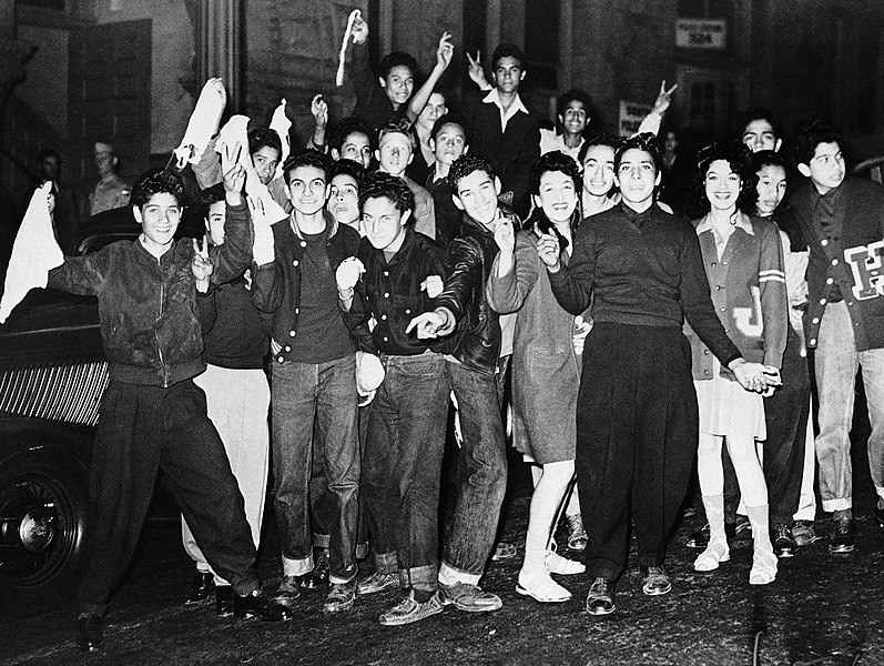 Zoot Suit Rioters celebrating Smiling young Zoot Suit rioters wearing letter sweaters, jeans, and wide leg pants make V signs