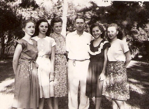 The Allen Family Five women in dresses stand with one man in shirt in pants, outside.