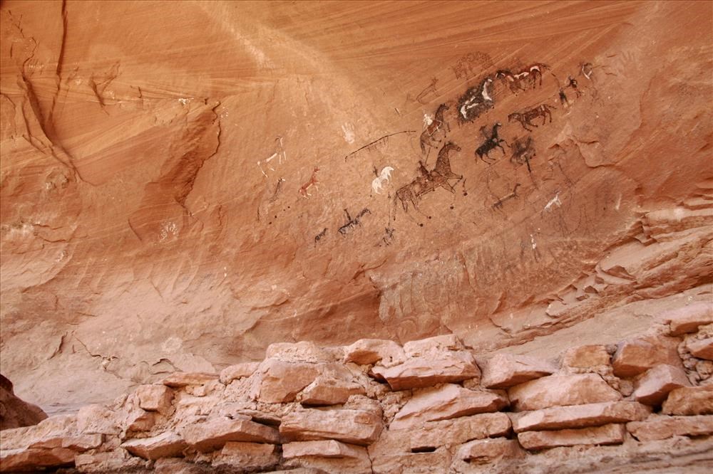 Pictographs of horses and riders on a rock face