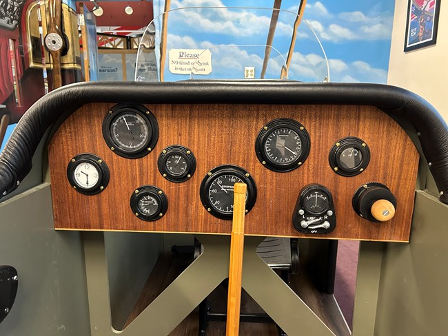 A close up view of the cockpit interior. Replica gauges are set into a veneer wood interior.
