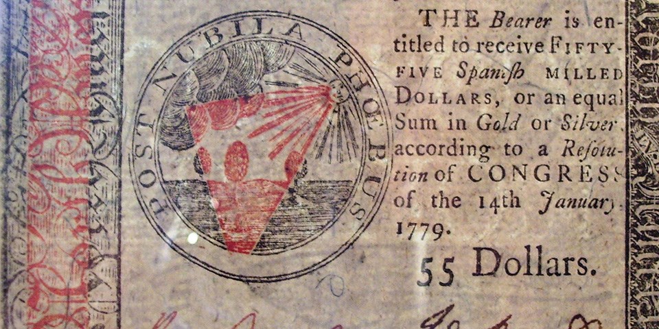 Continental money 55 dollar note from 1779 showing the sun and an open field.