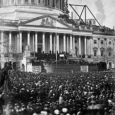 A large crowd stands in front of the Capital Building. Abraham Lincoln is being sworn in.