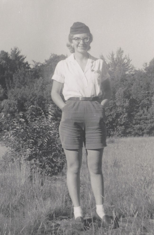 Georgiana Fry stands in a prairie wearing shorts, white blouse, and Girl Scout cap.
