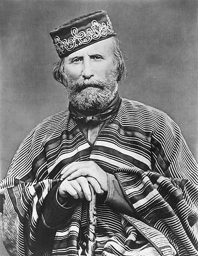 gentleman wearing a hat and holding a cane while sitting for a picture