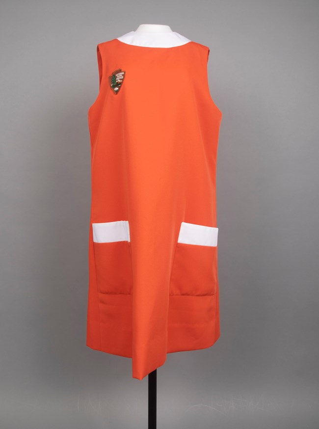 Orange apron dress with white trim on a mannequin