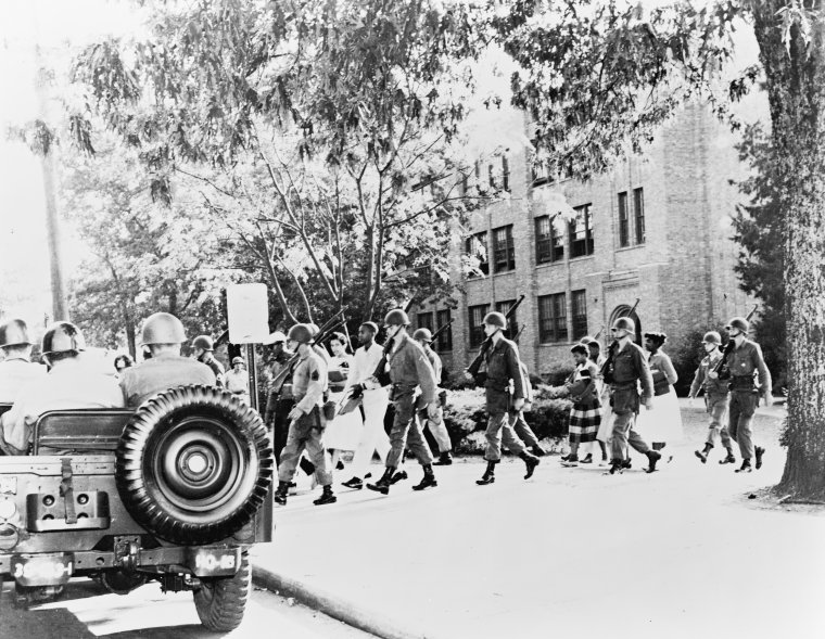 Black and white photo of national guard members escorting students away from school