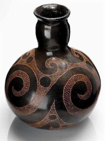 A long-necked brown piece of pottery with a swirling design.