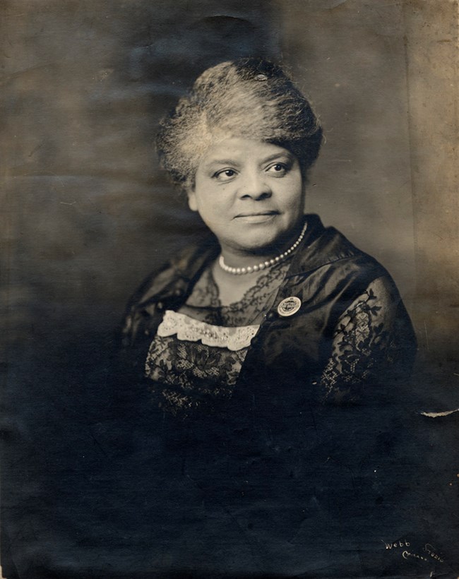 Black woman wearing a lace dress and a pearl necklace