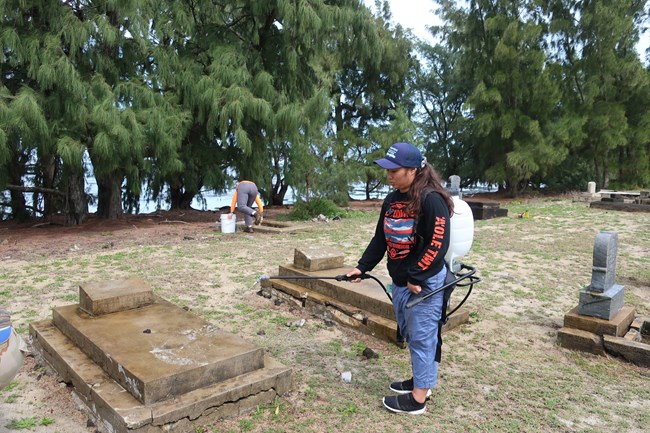 Emma Tanigawa rinses a grave marker she just cleaned among graves at Kalaupapa National Historical Park.