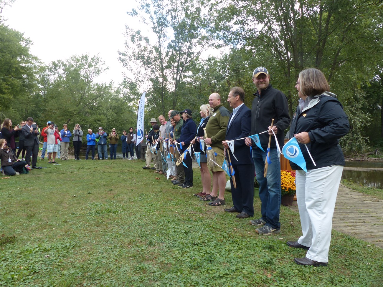 People standing in a line holding a long ribbon together