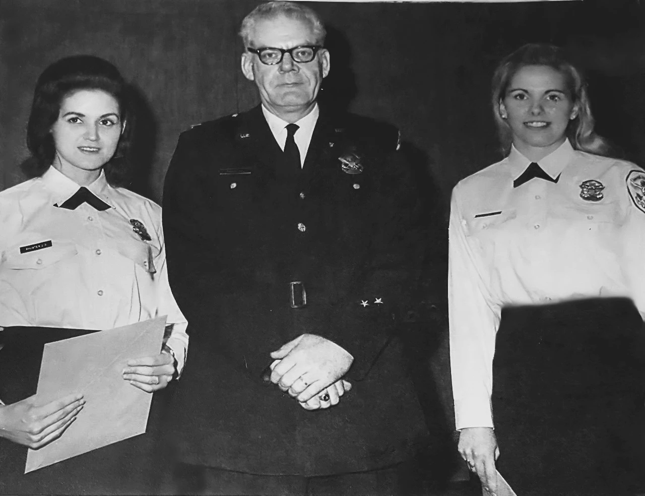Judy Schuster, Chief Fallon, and Paulette Dabbs Two police women in uniform pose standing on either side of a policeman.