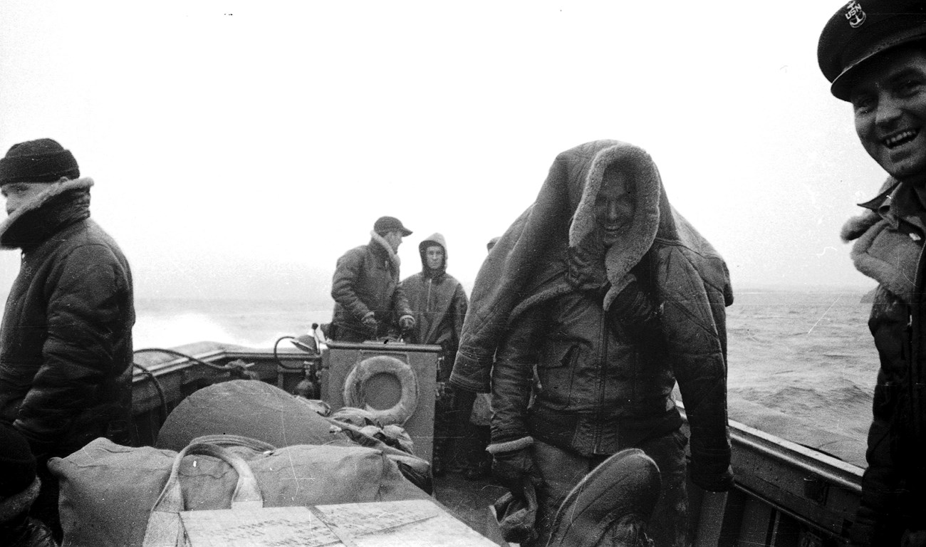 Men in winter gear on a boat in the water