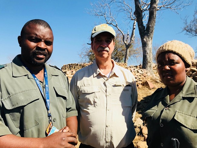 two men and a woman posing for picture, the middle man has an NPS uniform while the other two have green uniforms from south africa's national parks
