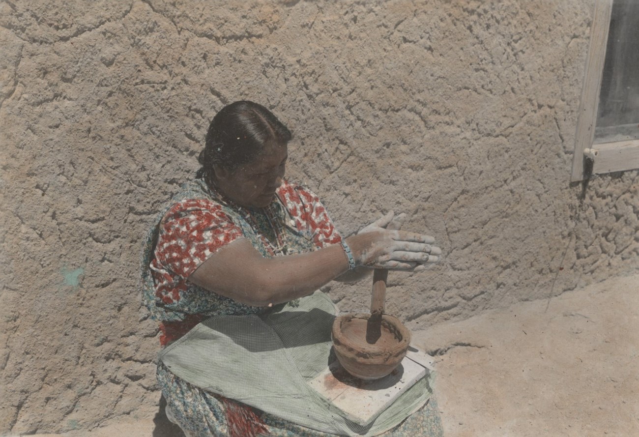 Legoria Tafoya rubs clay between her hands to make long pieces to coil around a pot.