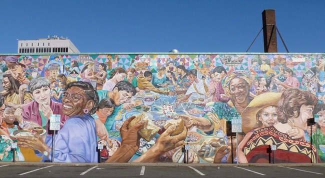 Colorful outdoor mural depicting people sharing a meal