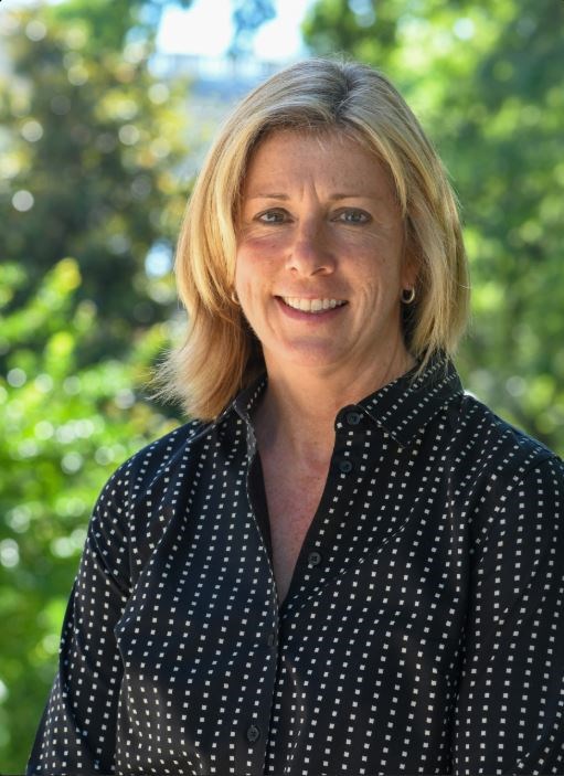 Associate Director Joy Beasley A blonde woman in a black shirt smiling for a portrait photo.