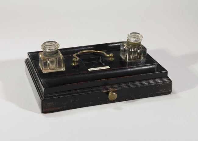 Black wooden inkstand with two glass ink jars.