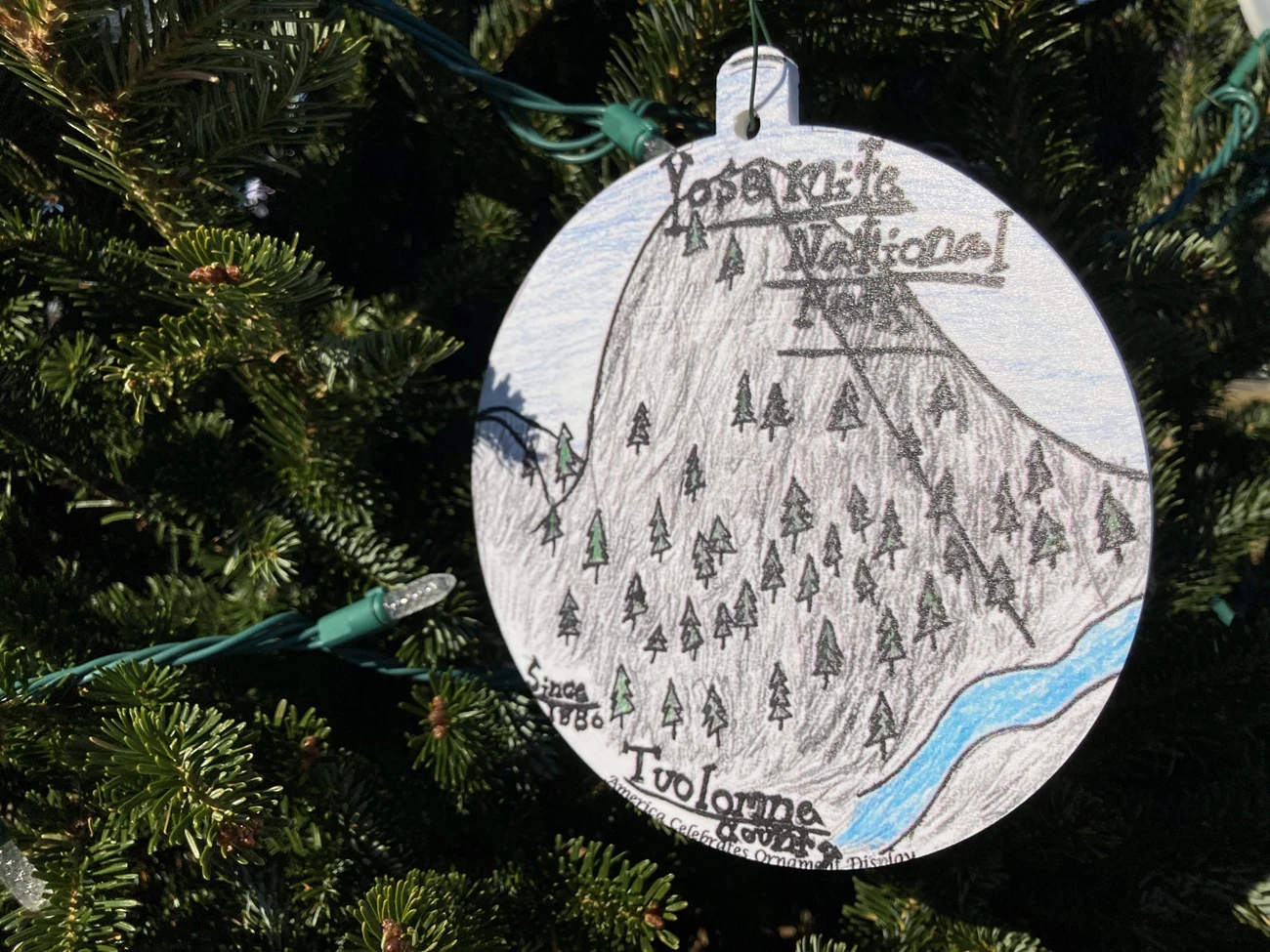 yosemite national christmas tree 2021 ornament with drawing of a gray tall stone, portraying yosemite. Ornament is hanging from christmas tree