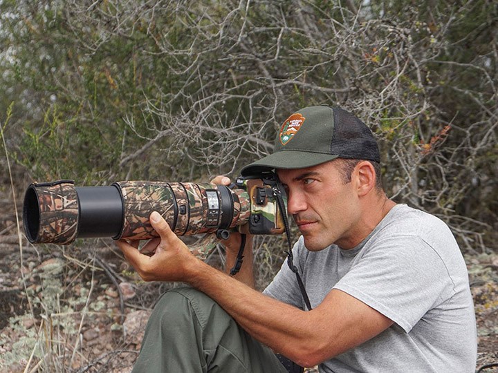 Biologist Gavin Emmons photographing prairie falcon nestlings with a telephoto lens.