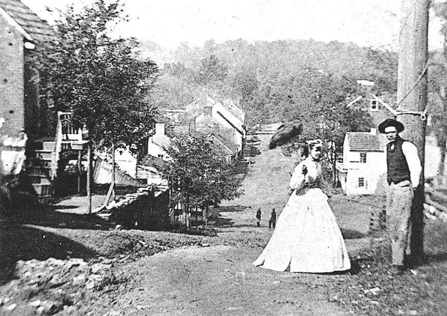 Black and white photo of man and woman standing in dirt road.