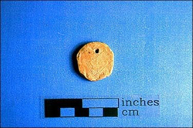 This pendant is a flattened bullet, shaped and drilled and probably worn as a makeshift dogtag, or maybe used as a favorite poker chip which never made it to the next game.