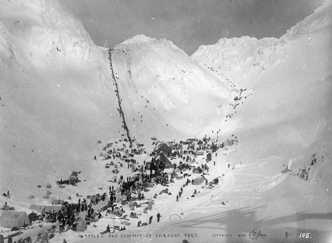 Mountain side with men in a line going over the pass